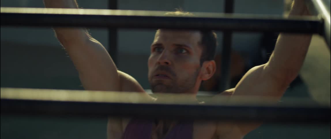 A man is outside exercising on monkey bars in a park