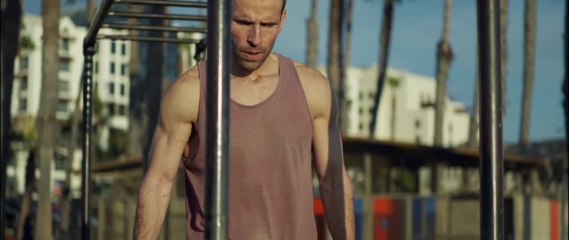 A man is walking outside underneath some playground equipment