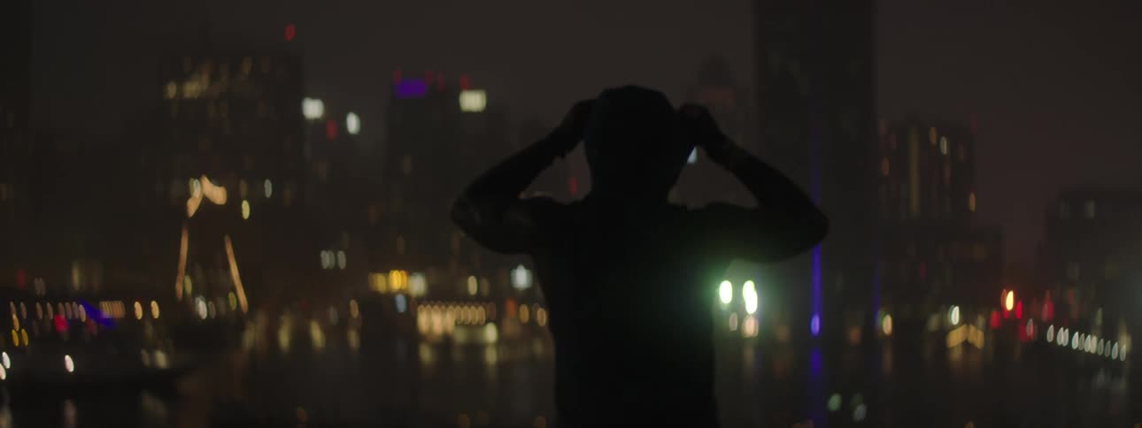 A young person is outdoors at night time in the city down town