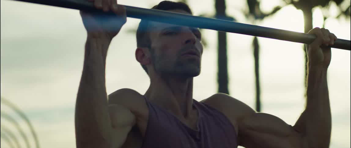 A young man is working out outdoors in the middle of the day