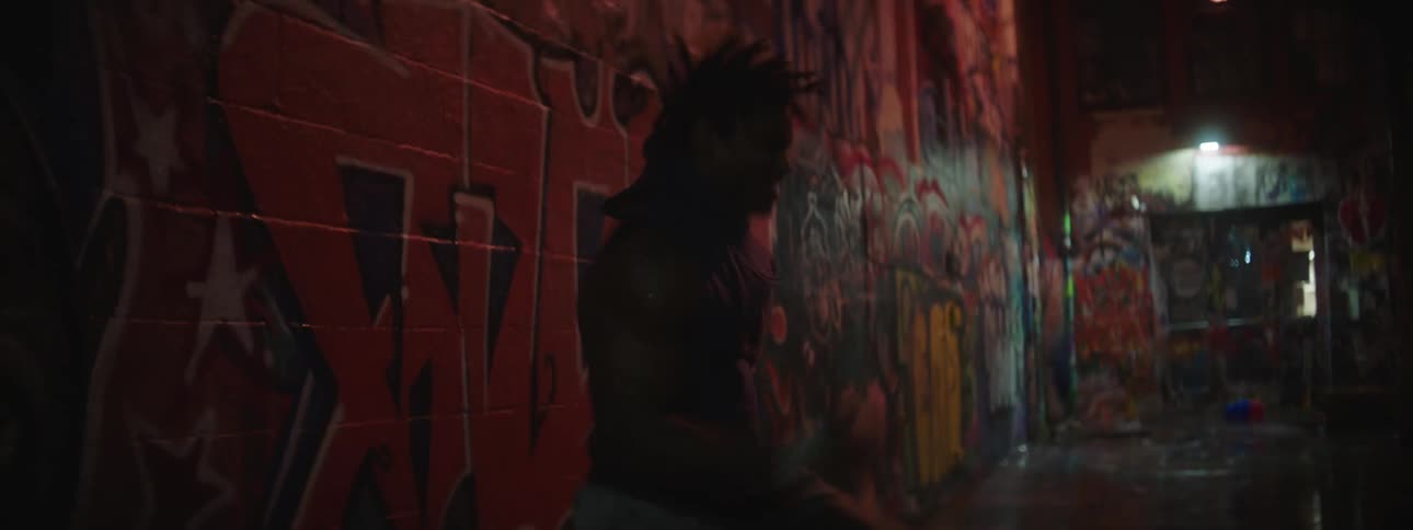 A young black man is working out inside by some graffiti that have words on it