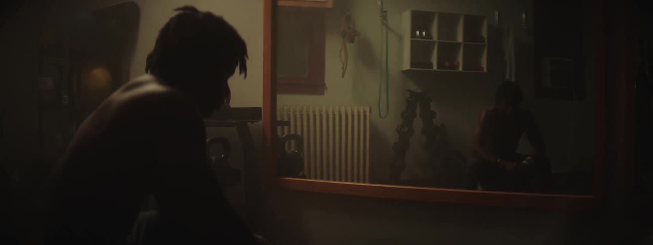 A young black man is sitting down inside of his house