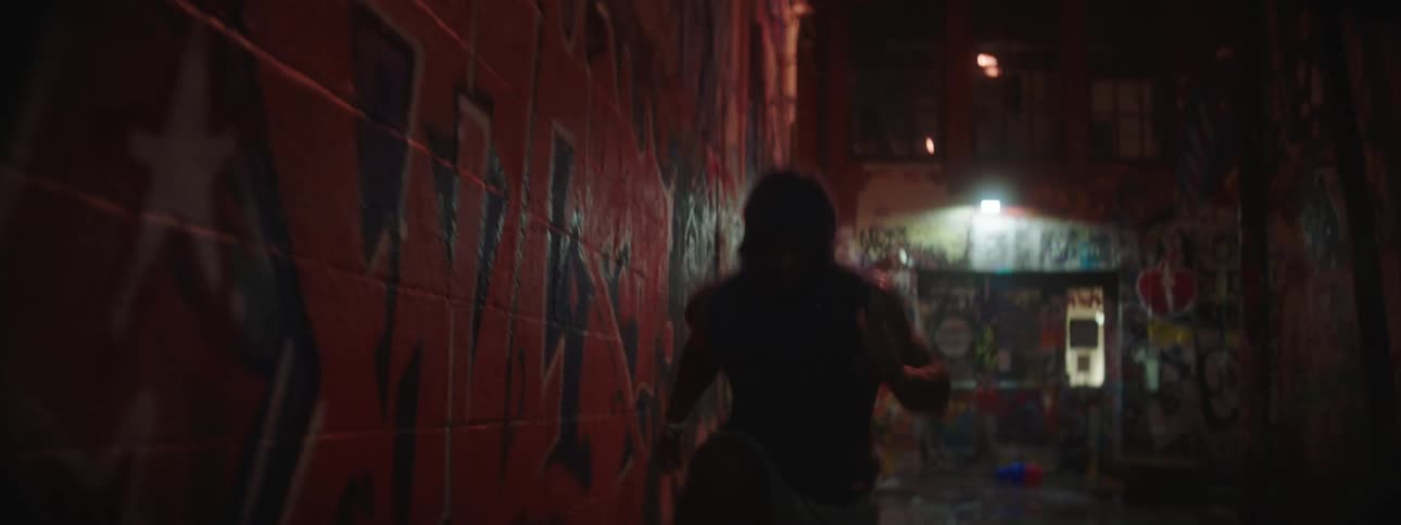A man jumping in an alley at night