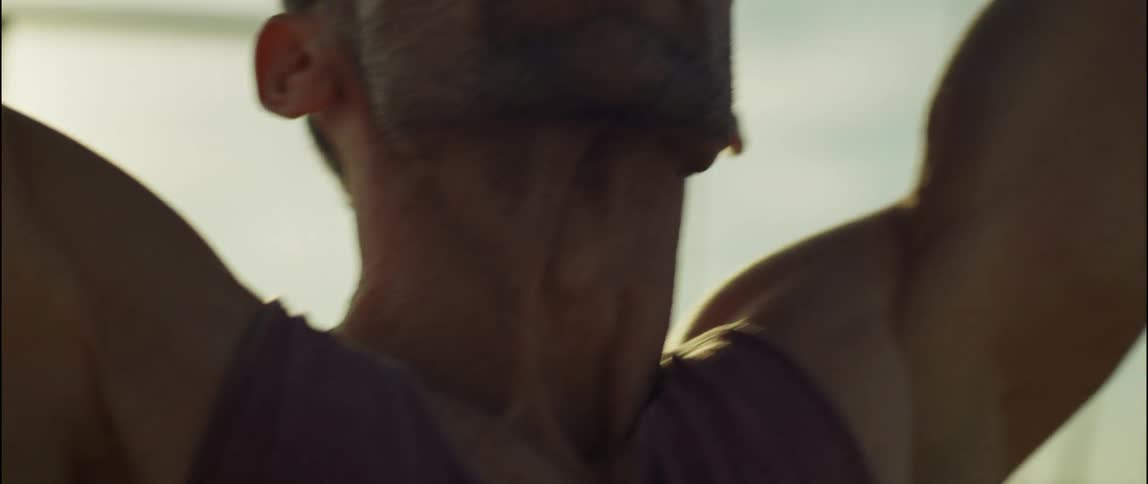 A man is stretching his arms outdoors at dusk