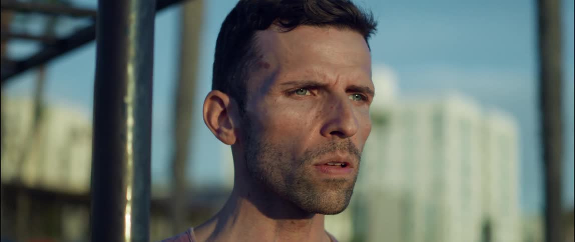 Man relaxes and breaths deeply after exercising on monkey bars near apartment buildings