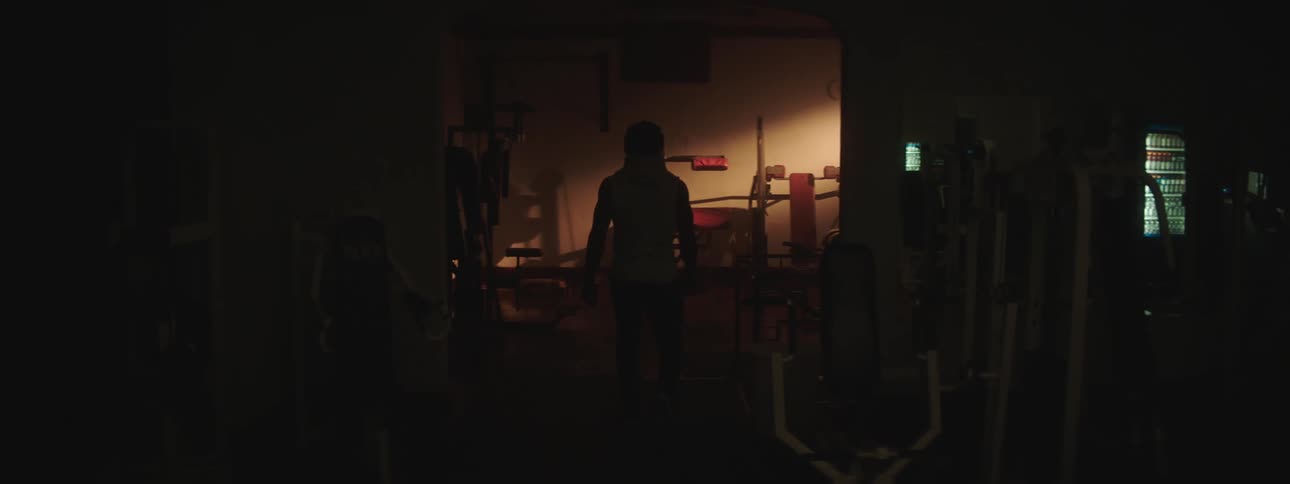 A person walks through a dark fitness center during the day