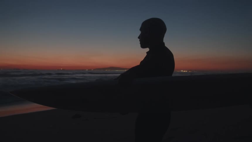 A man carries his surfboard on the beach