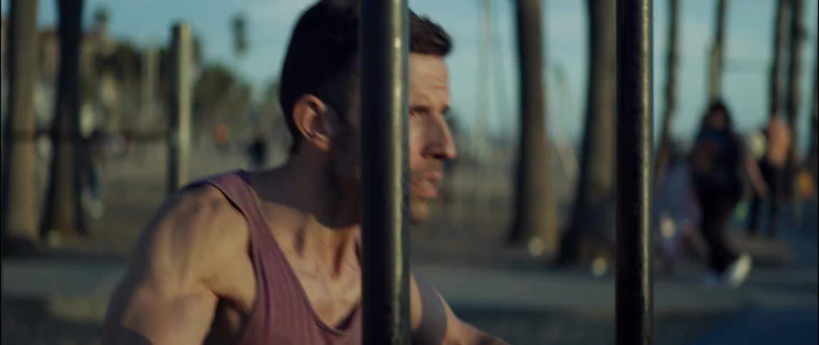 Young strong man working out on a public park on a beach at morning