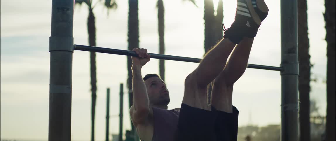 A young white man is working out outdoors in the middle of the day