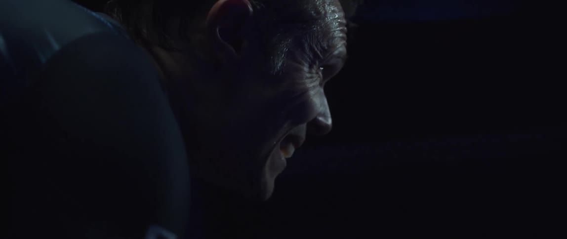 A man sweating and breathing heavily while riding a stationary bike