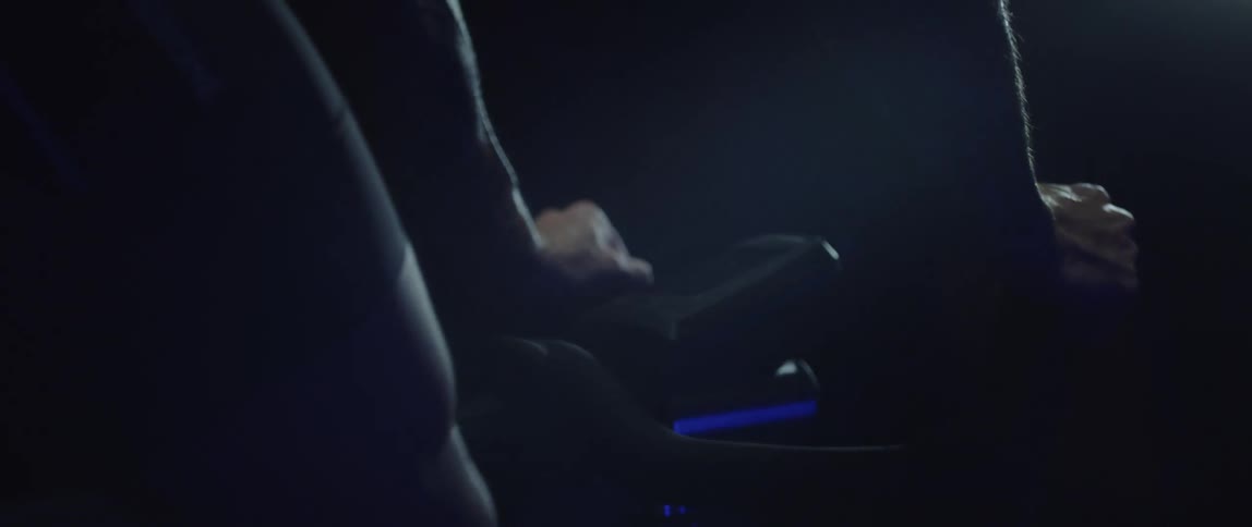 Close up of the hands of a man gripping the handlebar of a bicycle under blue lights