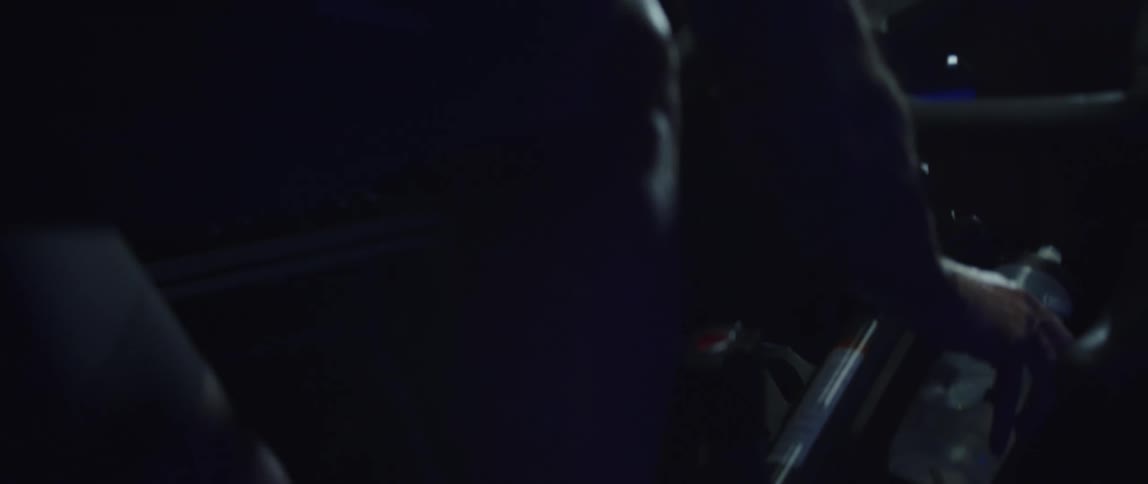 Athletic man riding a stationary bike and grabbing his bottle of water
