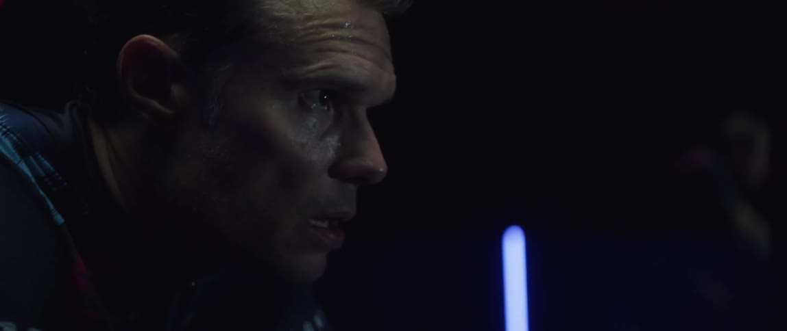 Head of a focused man that is exercising in a dark gym room