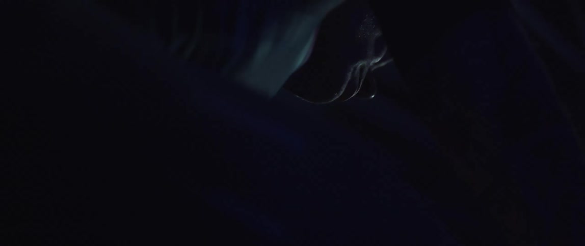 Man pedaling on a static bicycle inside a dimly lit room against a dark background