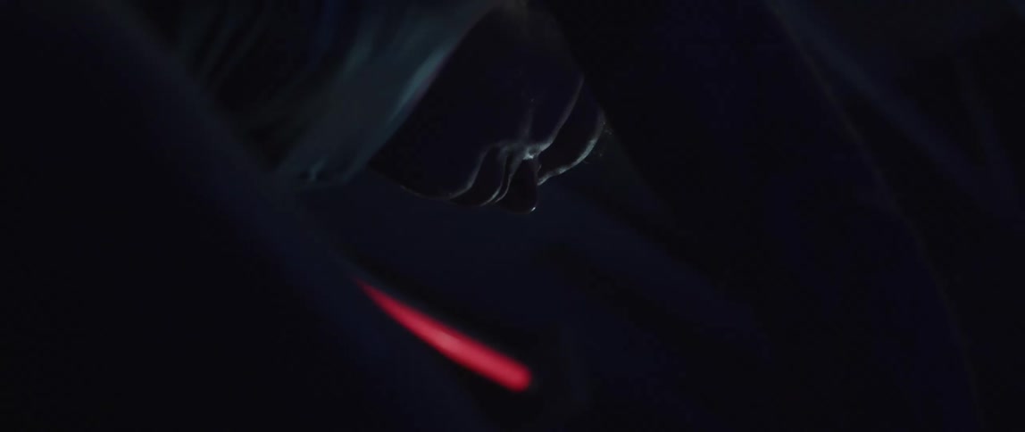 Man pedals on stationary bike in dark room lit by neon