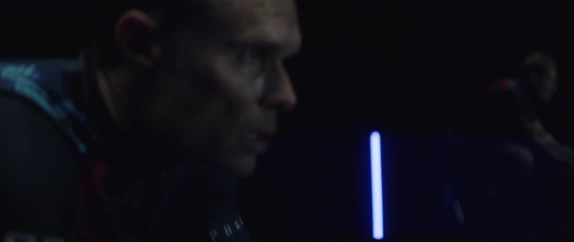 Focused sweaty man exercising on a stationary bike in a dark room