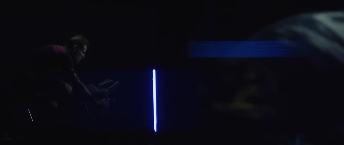 Man exercises by pedaling on stationary bike in a dark room