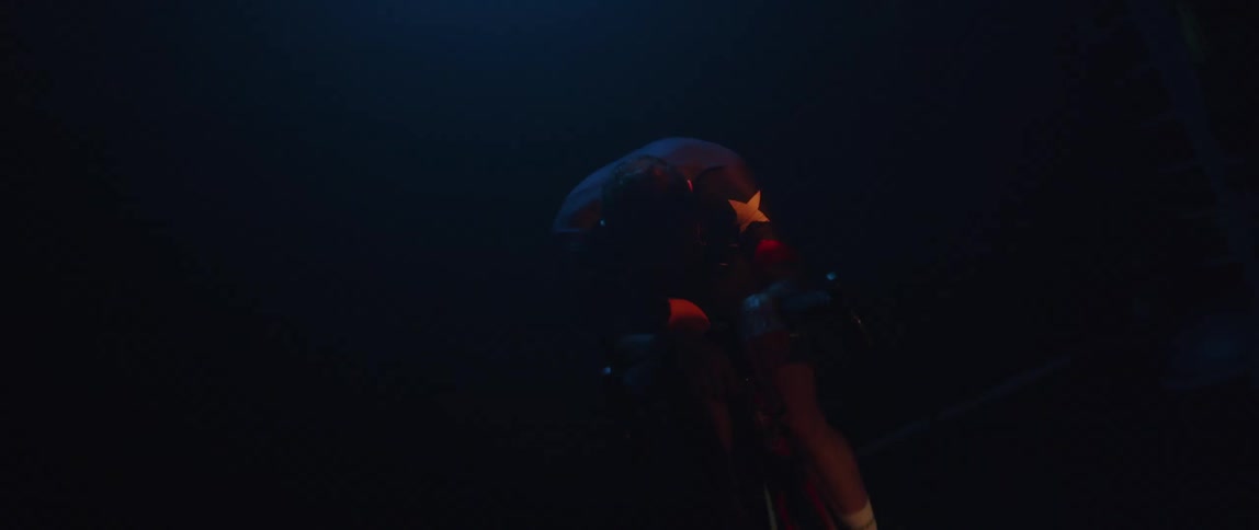 A man pedals on an exercise bike in a dark room