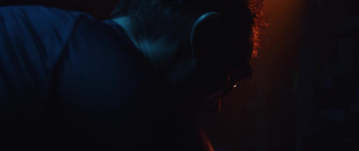 A man hangs his head as he moves under a red light