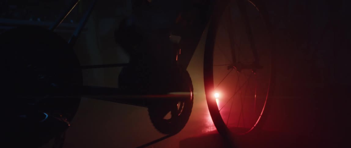 A man riding a stationary bike with a bright light on the ground