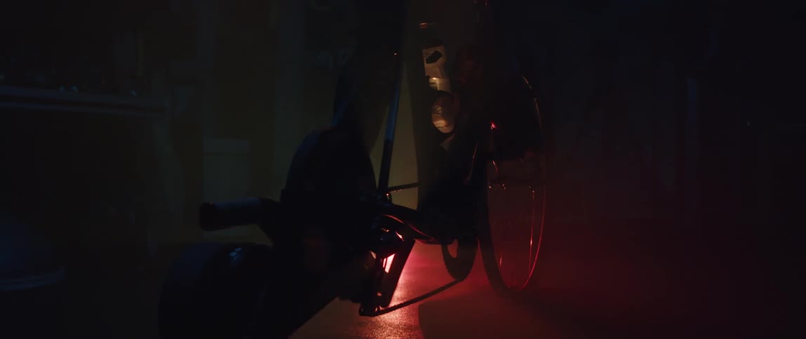 A person pedals an exercise bike in a dark room