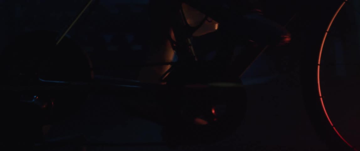 Close up of the gears and pedals of a static bicycle being pedaled inside a dimly lit room