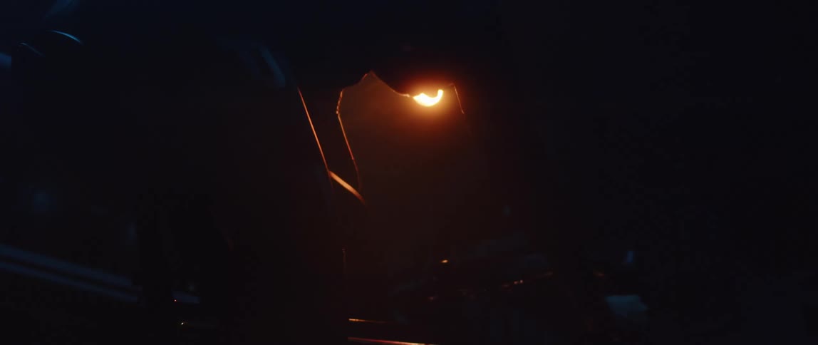 Close up silhouette of the legs of a man pedaling on a static bicycle inside a dimly lit room
