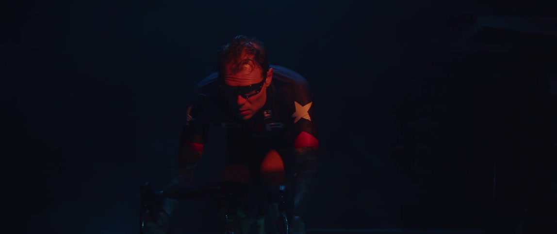 A man riding a stationary bike in darkness