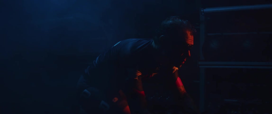 Determined and sweaty male cyclist with jersey shirt and tattoos rides exercise bike