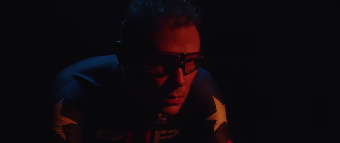 Male cyclist with glasses and jersey rides exercise bike