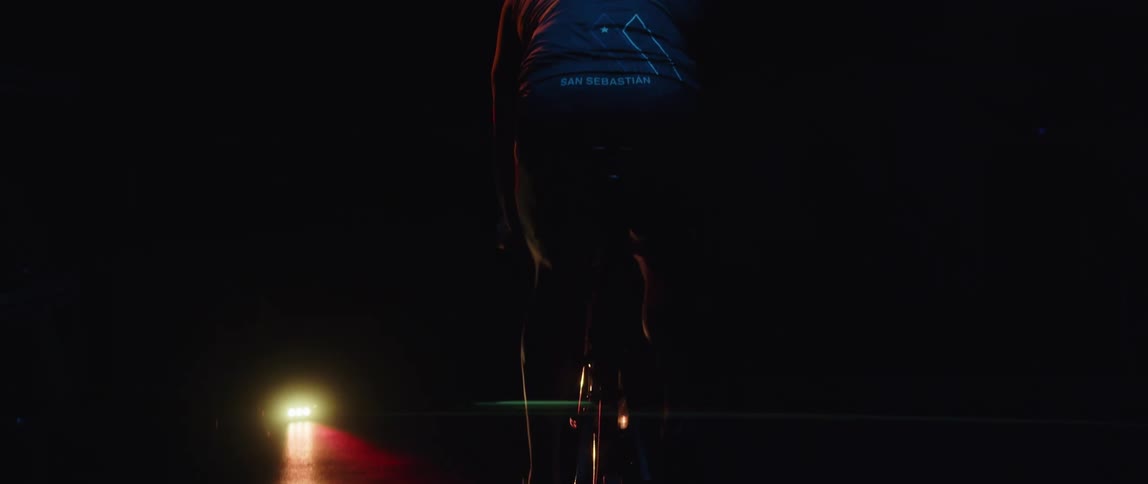 A bright light shines on a man pedaling an exercise bike in the night