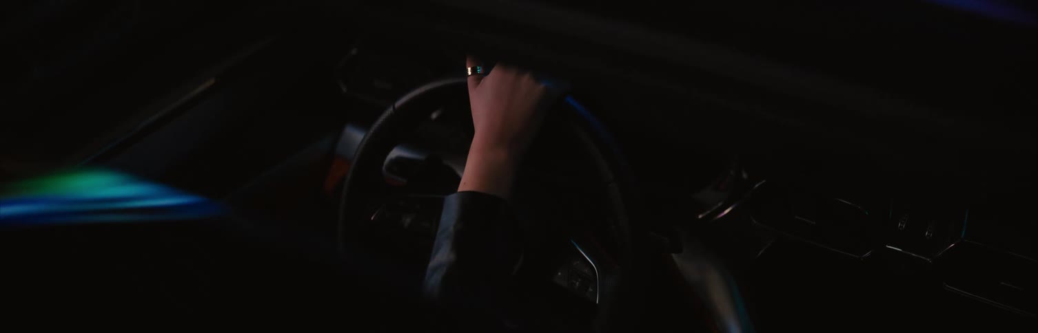 A flare of bright lights on a womans hand as she drives a car