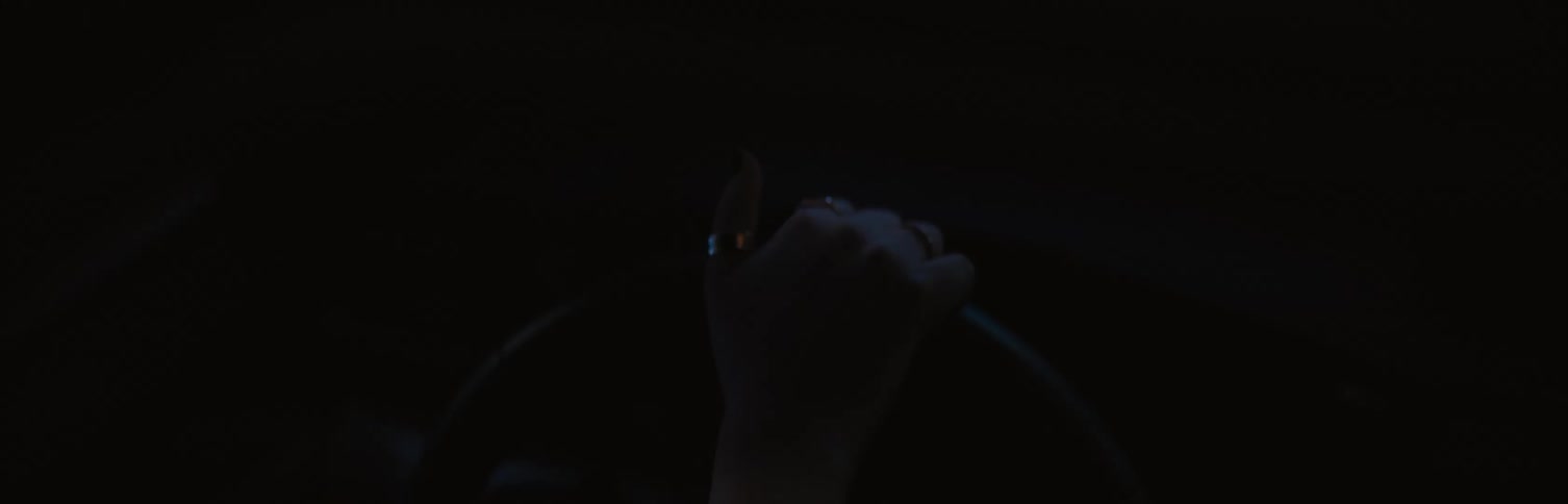 A flare of bright lights on a womans hand as she steers a car