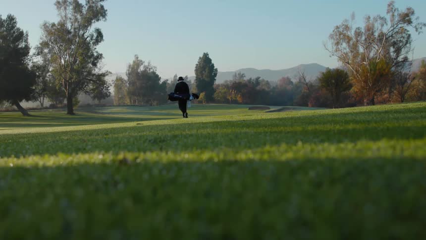 A person is walking on a grass field during the spring time