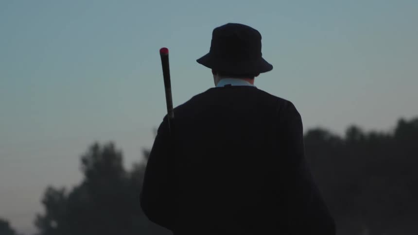 A man holds up his golf club while walking through a course