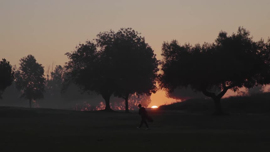 Silhouette of a person walking on the countryside in front of the setting sun