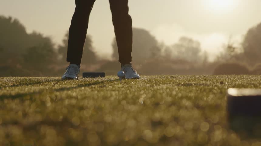 The legs and form of a golfer as he drives the ball off the tee