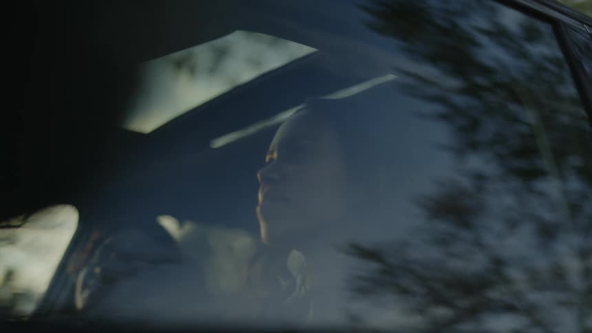 A teenage girl is sitting in the drivers seat of a car and she is laughing with a girl sitting next to her