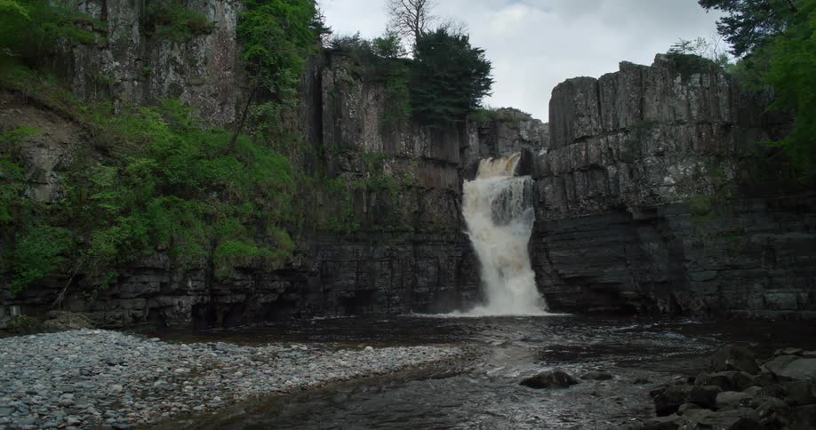 A powerful waterfall delivers water into a swiftly flowing river