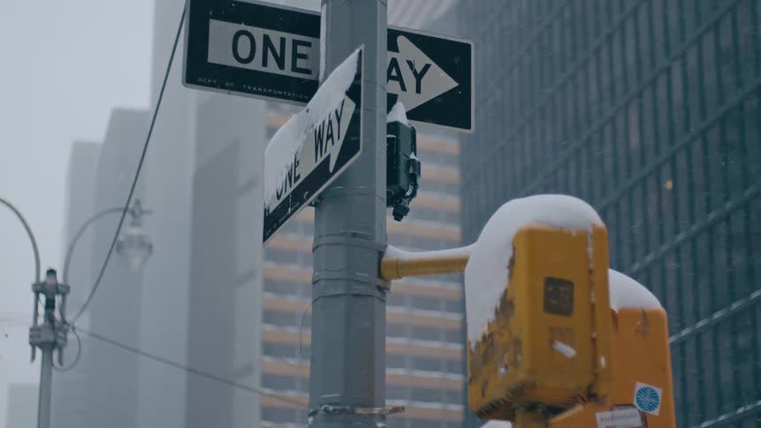 Snow falls onto ice covered sign at street corner in downtown