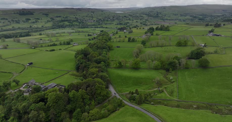 Vehicle moves along road through countryside in valley