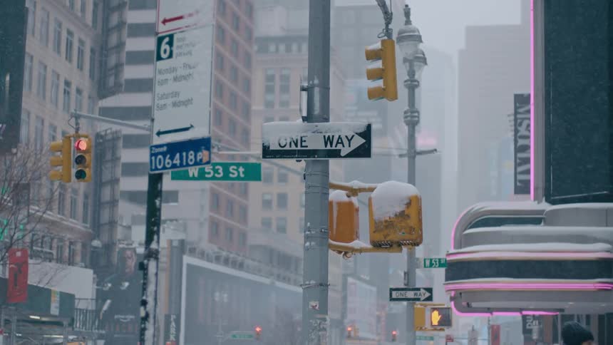 Ice crusts the signs and walk signals in city intersections as snow falls