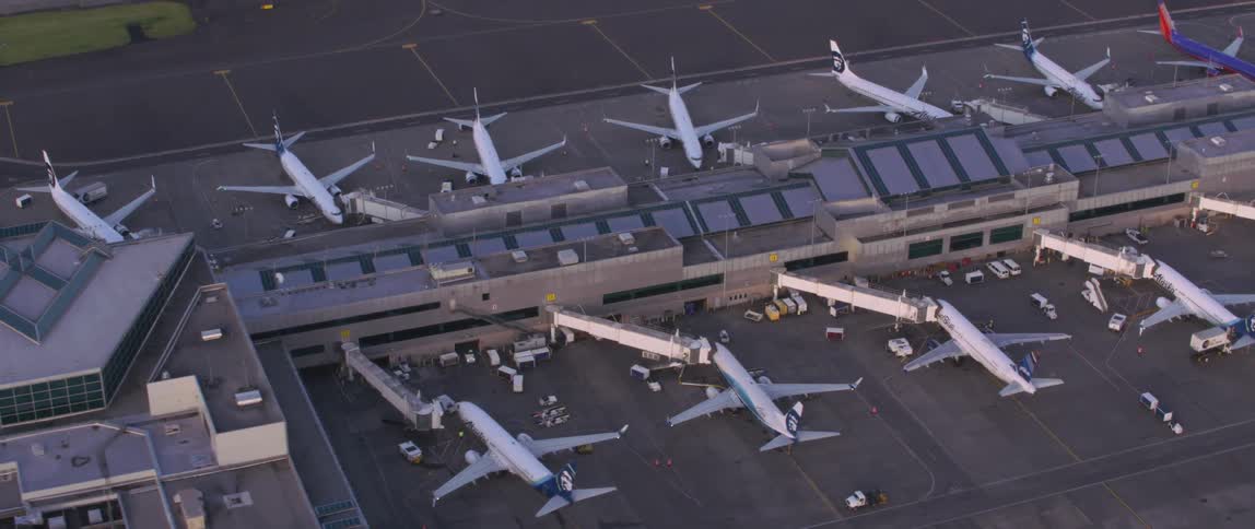 Airplanes sit parked at a long airport hangar