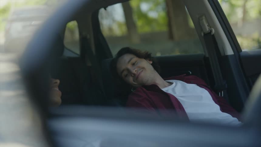 A man holding hands with his girlfriend inside a car