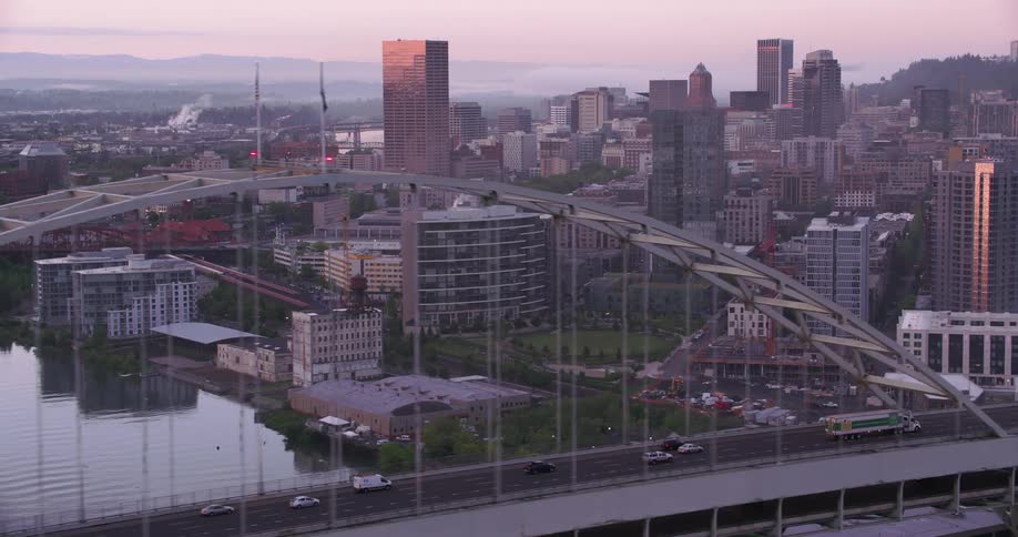 Cars and trucks traveling over the fremont bridge with city skyscrapers and skyline behind