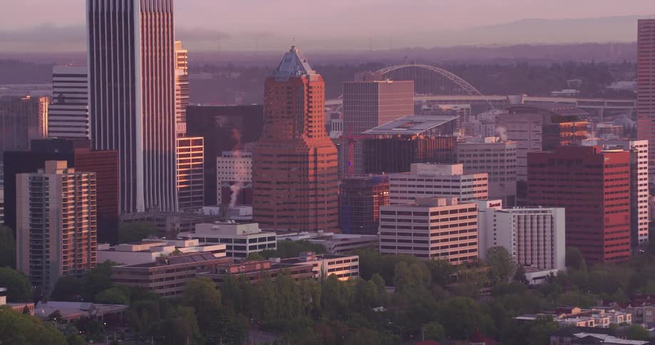 Office buildings in a downtown area with cars driving on streets and a river flowing through the city