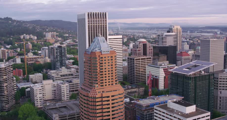 Construction crane stands in downtown of city stretching to red tinted horizon