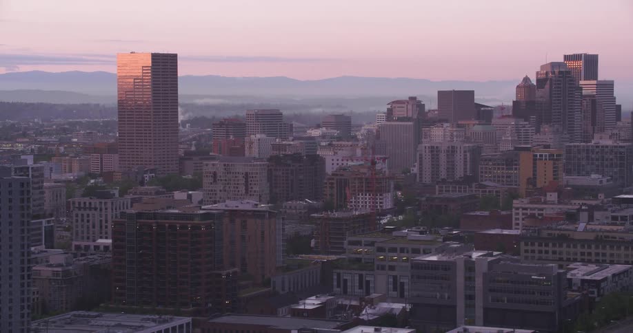 Downtown in the heart of the big city with tall buildings and skyscrapers and mountains in the distance