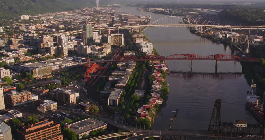An aerial view of a river running through a city with high rise office buildings and cars driving