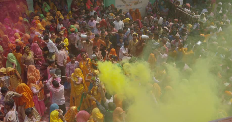 A crowd of people are celebrating and dancing as yellow smoke rises